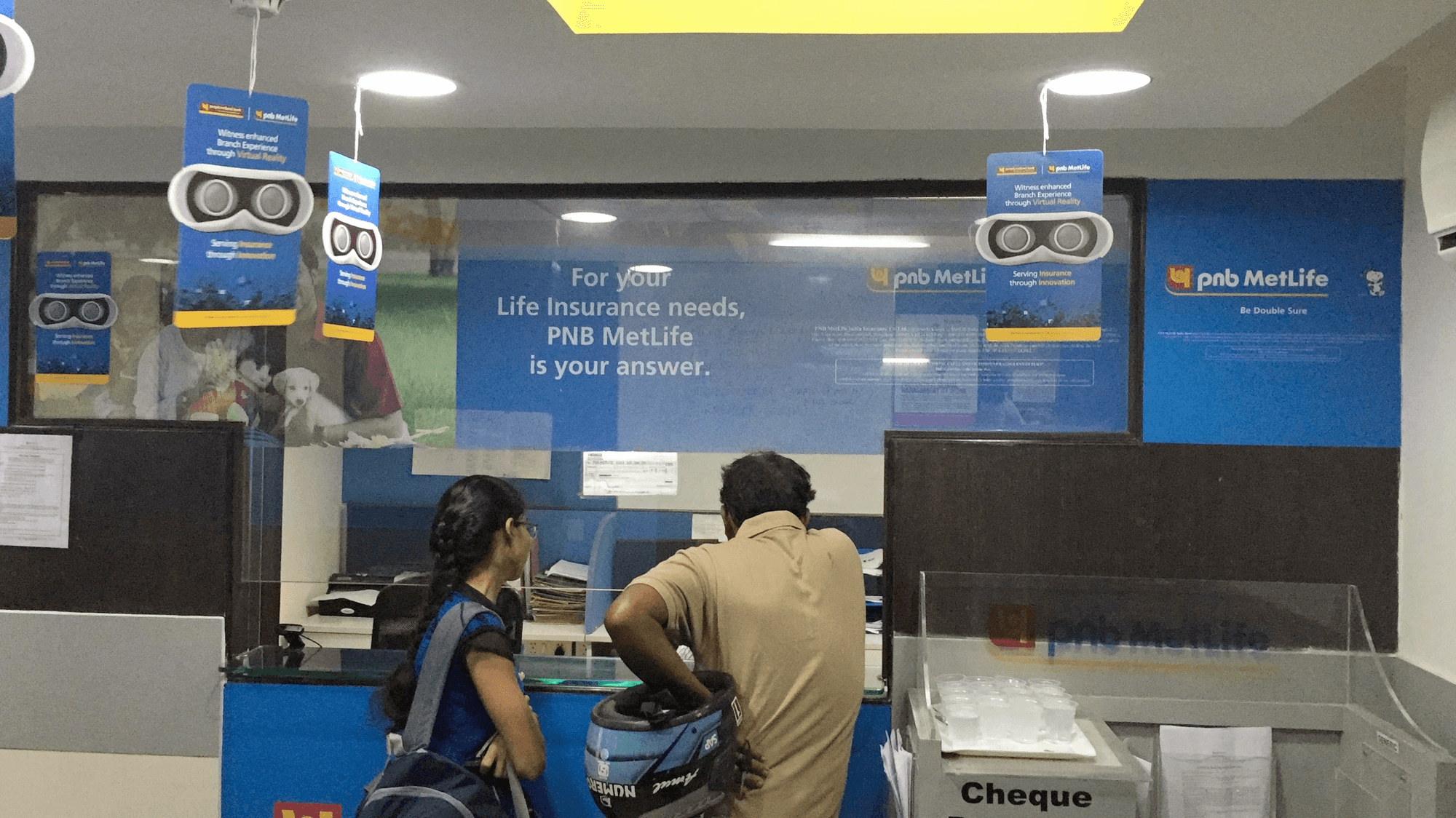 PNB MetLife branch decorated with conVRse VR branding: headset danglers, branded standees, and the 'Serving Insurance through Innovation' tagline