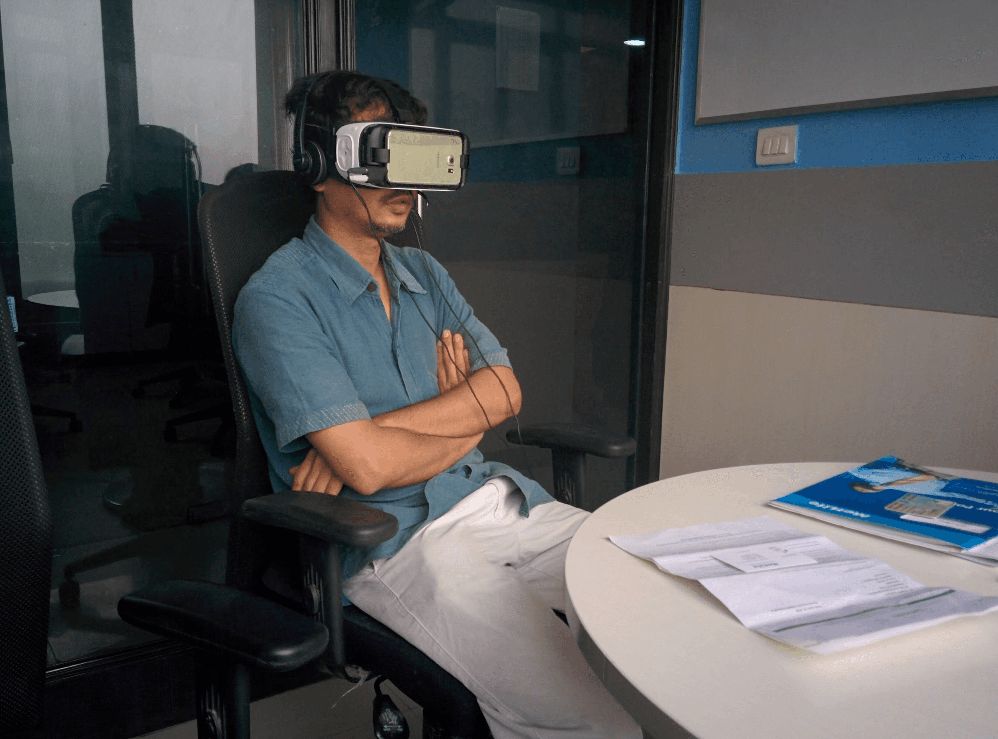 Customer seated in the MetLife branch trying the conVRse VR headset, MetLife documents on the table beside them